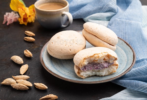 Meringues cakes with cup of coffee on a black concrete background and blue linen textile. Side view, close up