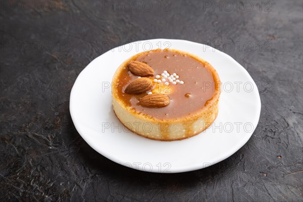 Sweet tartlets with almonds and caramel cream on a black concrete background. Side view, close up