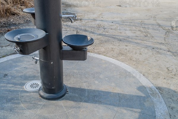 Black metal water drinking fountains near walkway in a public park in South Korea