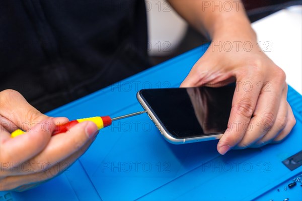 Close-up of an unrecognizable male technician repairing a phone in a workshop