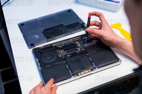 Close-up of an unrecognizable man repairing a digital tablet in a IT workshop