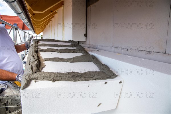 Construction workers insulate a house facade