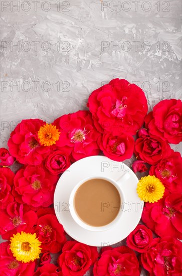 Red rose flowers and a cup of coffee on a gray concrete background. Morninig, spring, fashion composition. Flat lay, top view, copy space