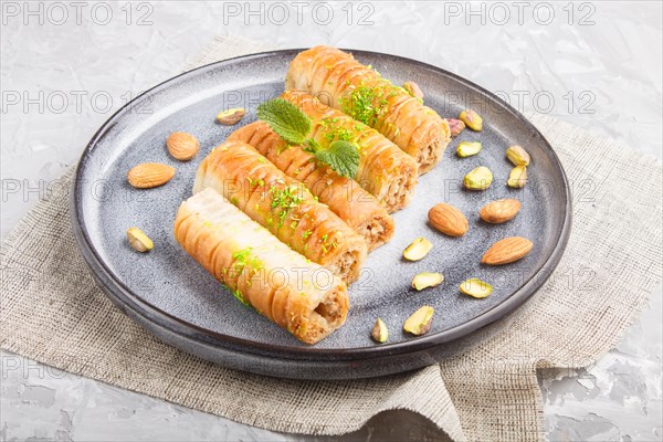 Baklava, traditional arabic sweets in gray ceramic plate on a gray concrete background. side view, close up
