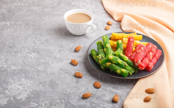 Set of various traditional turkish delight (rahat lokum) in blue ceramic plate with cup of coffee on a gray concrete background. side view, copy space