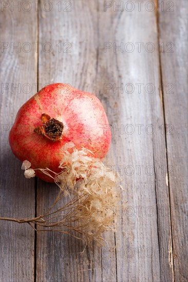 Ripe garnet with a branch on a rustic wooden background