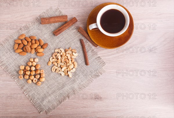 A cup of coffee, cinnamon, almonds, hazelnuts, cashew on a linen napkin. Still life. Closeup. copy space, top view
