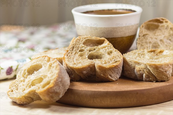 Sliced bread and a cup of coffee on a wooden board and linen tablecloth