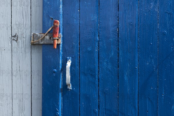 Blue sliding door with handle and red wooden splint to close the wooden wall of a fisherman's hut, Hvide Sande, Midtjylland region, Denmark, Europe