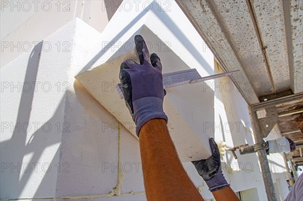 Construction workers insulate a house facade