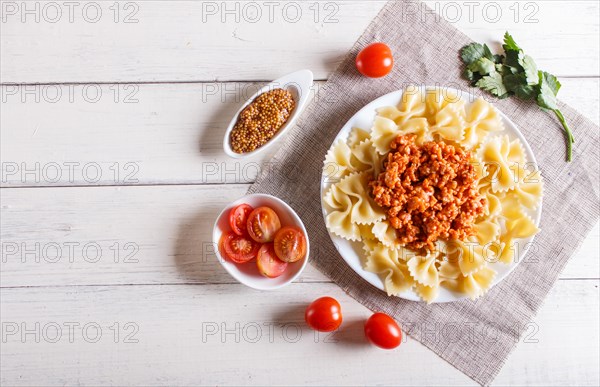 Farfalle bolognese pasta with minced meat on white wooden background. top view, copy space