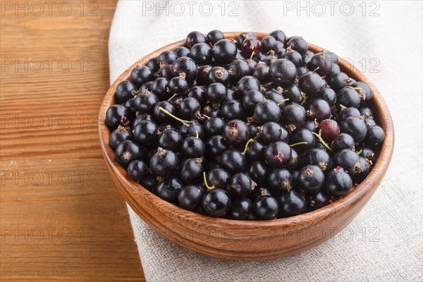 Fresh black currant in wooden bowl on wooden background. side view, close up