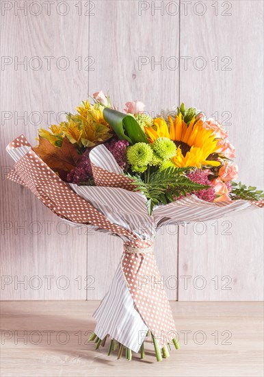 Bouquet of alstroemeria, sunflower, roses, chrysanthemum on a wooden background. floristic composition
