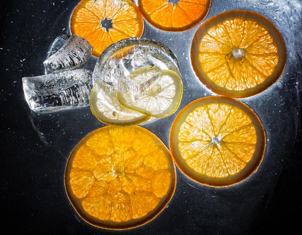 Transparent slices of fresh oranges and lemons on the glass with ice