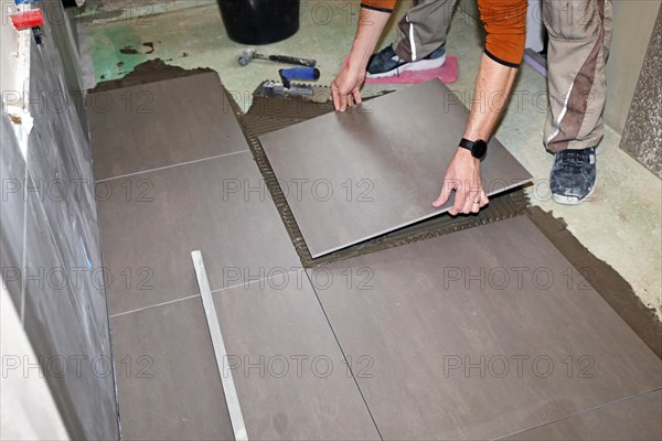 Tiler lays modern large floor tiles in a bathroom