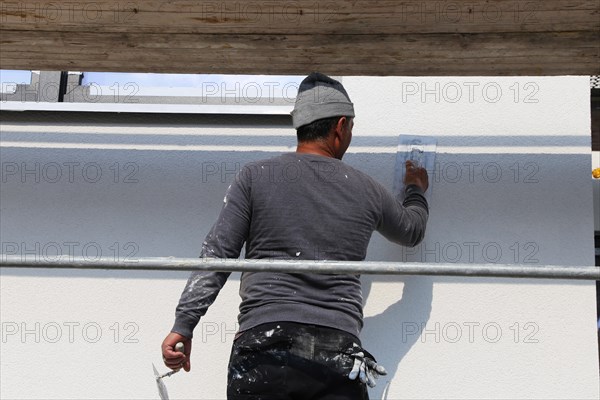 Painter and plasterer working on the facade of a new residential building (Mutterstadt development area, Rhineland-Palatinate)