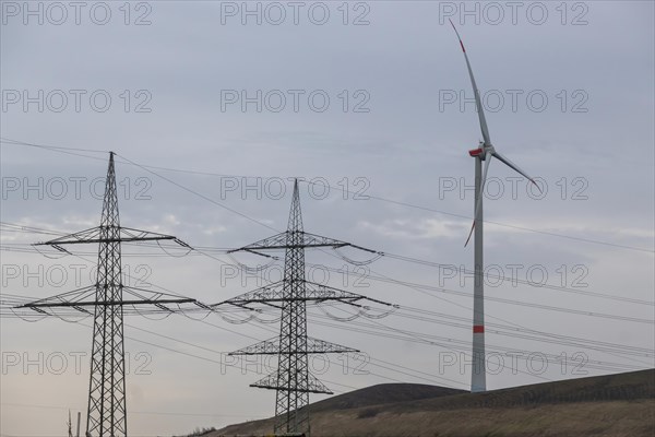 High-voltage pylons with wind turbine in German industrial landscape