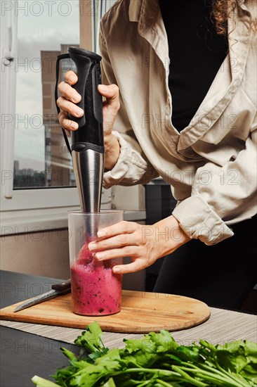 Unrecognizable woman making purple smoothie with banana and black currant