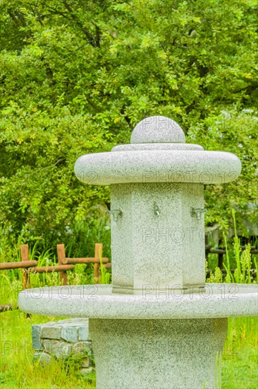Large hand washing water fountain in a public park with lush green foliage in South Korea