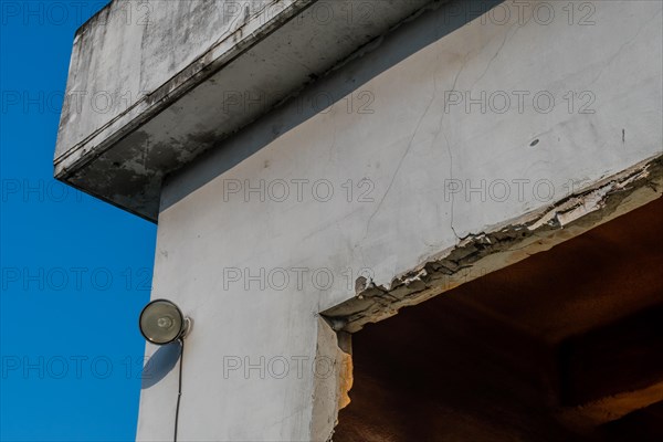 Flood light mounted on outside wall of abandoned concrete building with blue sky in background in South Korea