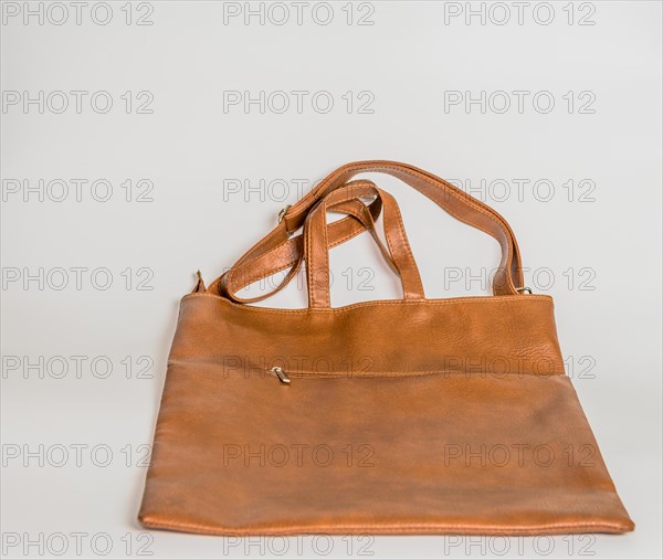 Brown leather shoulder bag with front zipper pocket isolated on white background