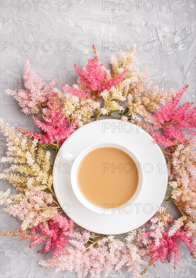 Pink and red astilbe flowers and a cup of coffee on a gray concrete background. Morninig, spring, fashion composition. Flat lay, top view, copy space