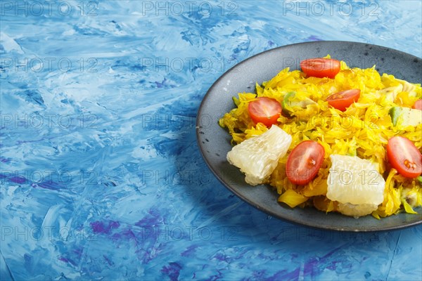 Fried pomelo with tomatoes and avocado on blue concrete background. side view, copy space, myanmar food