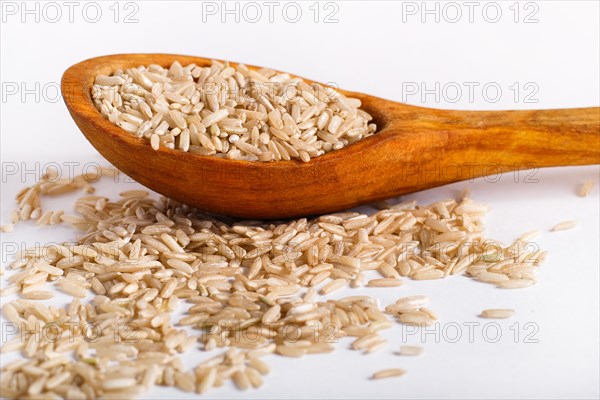 Pile of brown rice in a wooden spoon isolated on white background