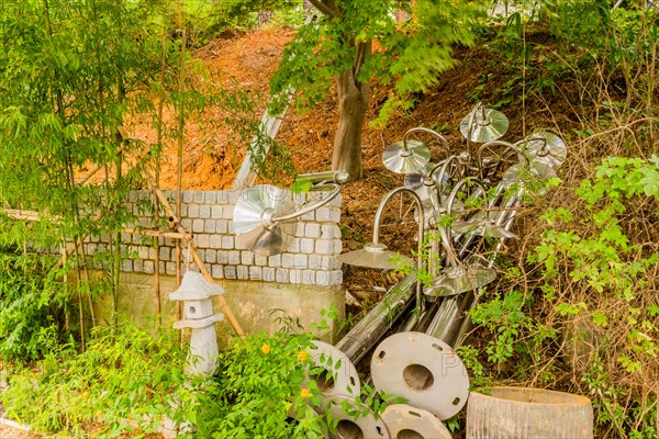 Chrome plated lamp posts laying on hillside in wooded area next to brick wall in South Korea