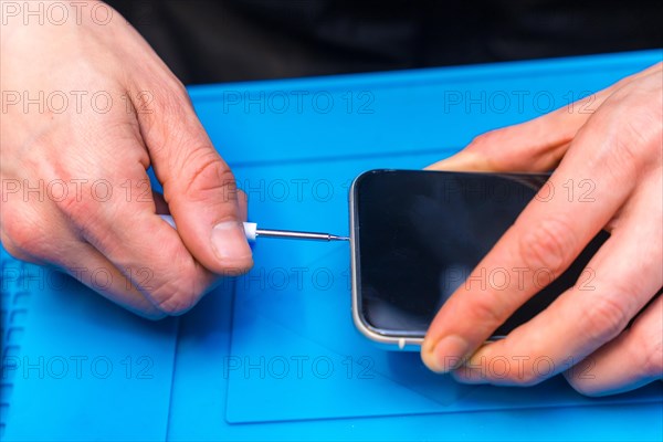 Close-up of the hands of a male expertise repairing a mobile phone in a technology workshop