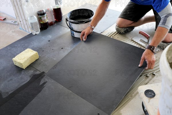 Tiler lays modern large floor tiles in a bathroom