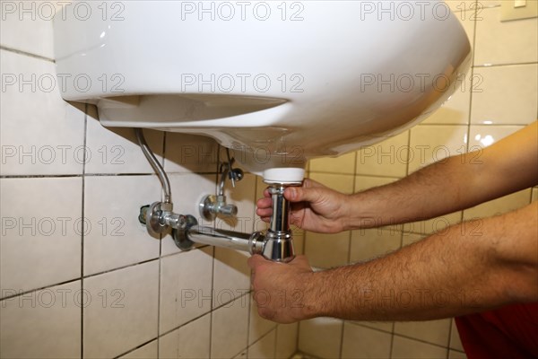 Plumber installs the siphon on a washbasin