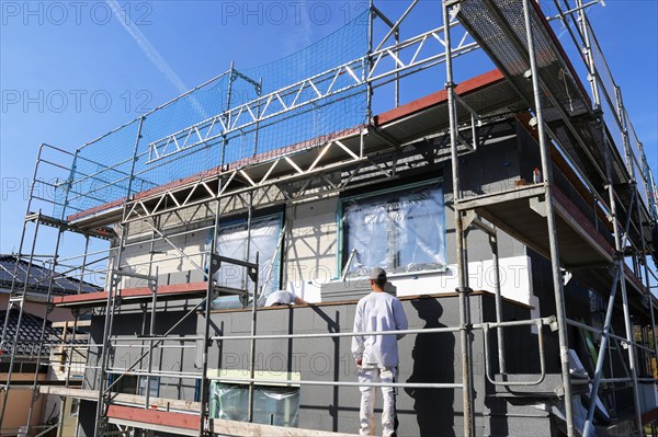 Construction workers insulate a house facade