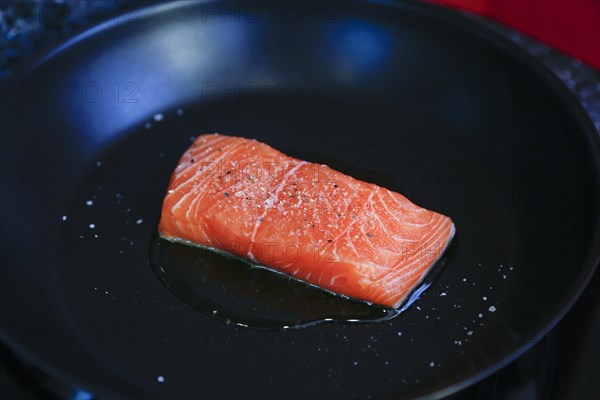 Preparation of Dreisam salmon with wild rice, raw salmon fillet in a pan, frying in oil, southern German cuisine, lemon sauce, salmon fillet, healthy eating, food, studio, fish dish, cooking, Germany, Europe