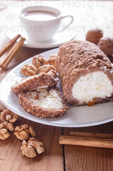 Roll cake with curd and walnuts isolated on white wooden background. close up