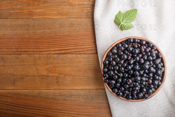 Fresh black currant in wooden bowl on wooden background. top view, flat lay, copy space