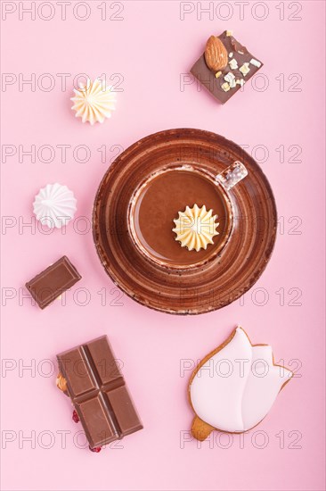 Cup of hot chocolate and pieces of milk chocolate with almonds on pink background. top view, flat lay, close up