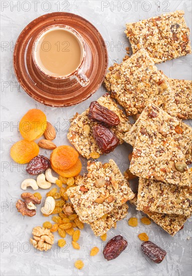 Homemade granola from oat flakes, dates, dried apricots, raisins, nuts with a cup of coffee on a gray concrete background. Top view, flat lay, close up
