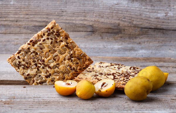 Biscuits with flax, sesame and sunflower seeds and yellow quince fruit on a rustic wooden background