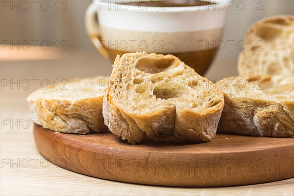 Sliced bread and a cup of coffee on a wooden board and linen tablecloth