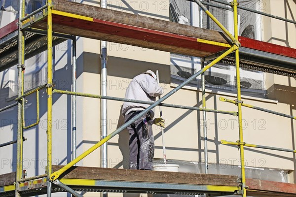 Painter painting the facade of a new residential building (Mutterstadt development area, Rhineland-Palatinate)