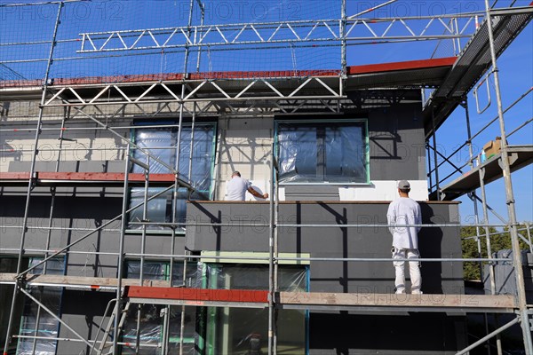 Construction workers insulate a house facade