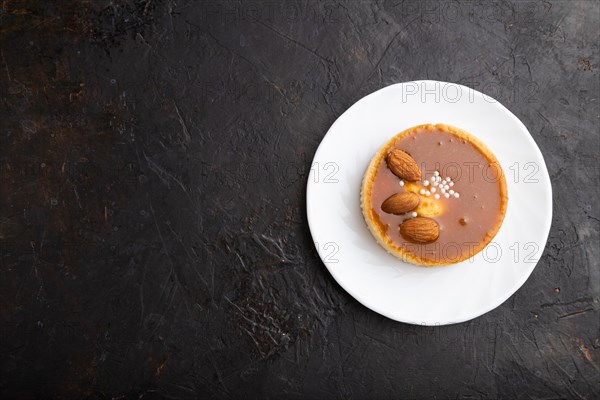 Sweet tartlets with almonds and caramel cream on a black concrete background. top view, flat lay, copy space