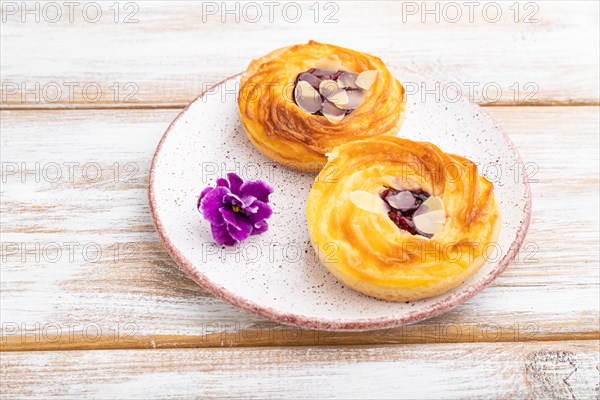 Small cheesecakes with jam and almonds on a white wooden background. Side view, close up