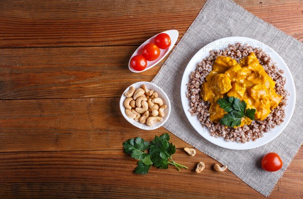Buckwheat with chicken curry sauce with cashew on brown wooden background. top view, copy space
