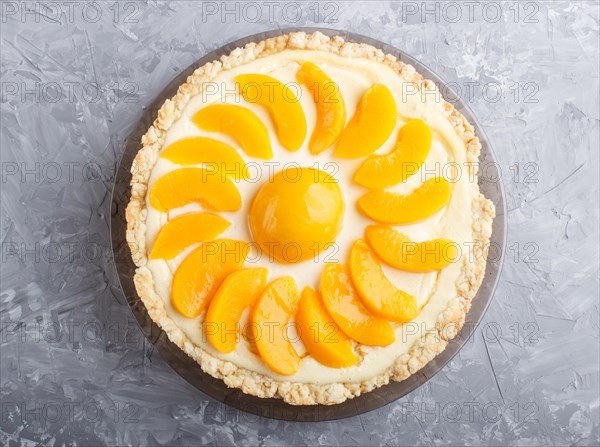 Round peach cheesecake on a gray concrete background. top view, flat lay, close up