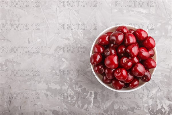 Fresh red sweet cherry in white bowl on gray concrete background. top view, flat lay, copy space