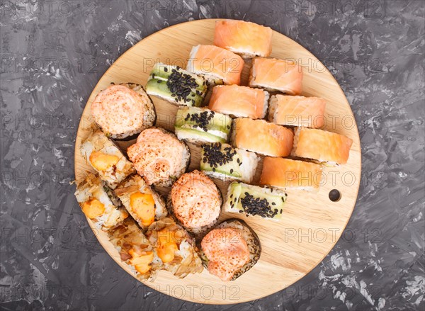 Mixed japanese maki sushi rolls set on black concrete background. Top view, close up, flat lay