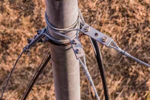 Top down view of wire cables attached to metal pole with brown grass blurred in background in South Korea