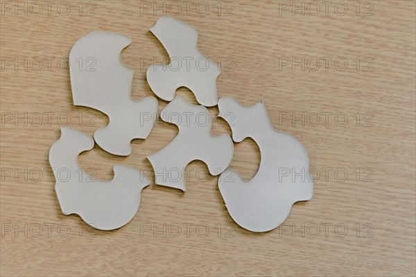 Assorted puzzle pieces laying upside down on brown wood grain tabletop